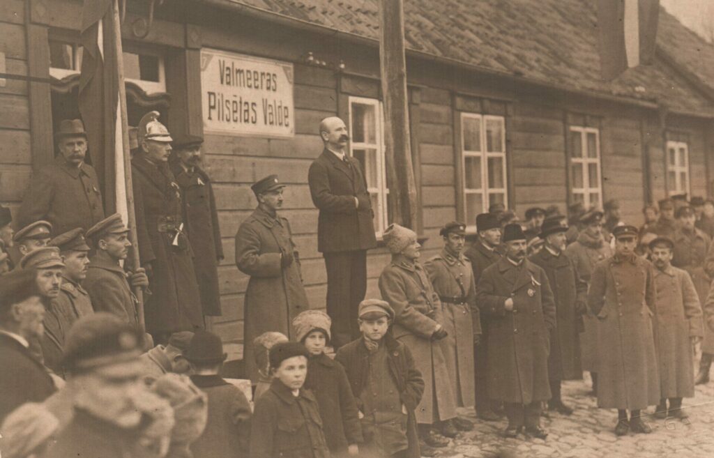Vēsturisks brīdis. 1920.gada 18.novembrī pie toreizējā pilsētas valdes nama. A.Melnalksnis stāv aizmugurē pirmais no labās.Pilsētas galvas Alberta Ziediņa svinīgās uzrunas laikā